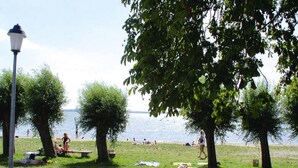 A park with picnic tables and people relaxing by the water. - Ferienhauser am Kummerower See, Verchen (Verchen)