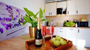 Une cuisine moderne avec des meubles blancs, un four à micro-ondes et un panier de fruits.