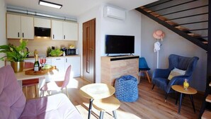 Un salon moderne comprenant un canapé, des fauteuils, une table basse, un téléviseur et un escalier.