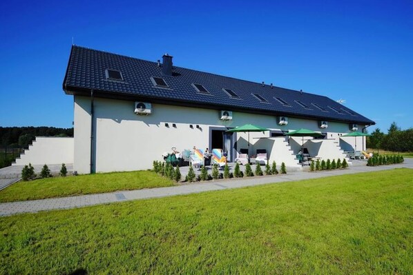 A modern building with a sloped roof, a covered entrance with a green awning, and a staircase leading to the entrance. - Comfortable and Spacious Holiday Home, Mielenko (Mielno)