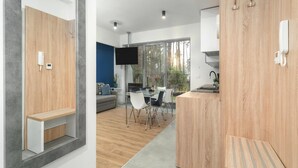 A modern kitchen with a built-in stove, a dining area with a table and chairs, and a large window offering a view of trees. - Comfortable Apartment Close to a Sandy Beach (Rewal)