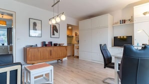 Ein modernes Wohnzimmer mit Sofa, einem kleinen Tisch, einem Schrank und einem Fernseher.