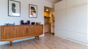 Eine moderne Küche mit Holzboden, weißen Schränken und einem Konsolentisch aus Holz mit elektronischen Geräten.