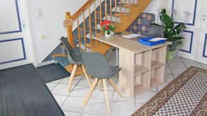 A room with a wooden staircase, a desk with chairs, a vase with flowers, and a patterned rug. - Ferienwohnung im Gutshaus Schulenbrook (Metelsdorf)
