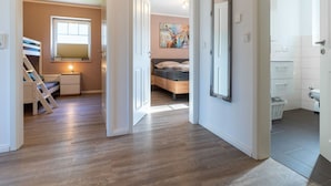 Un dormitorio moderno con literas, una mesita de noche y un espejo grande.