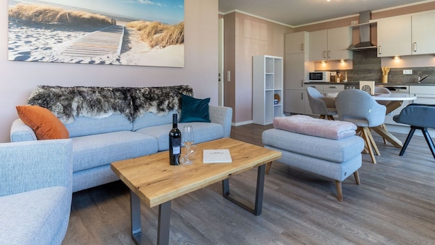 Una sala de estar moderna con un sofá, una mesa de centro y un cuadro con una escena de playa.