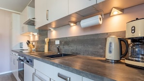 Una cocina moderna con un lavamanos de acero inoxidable, una tetera y una cafetera.