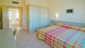 Un dormitorio con cama, armario, escritorio y silla.