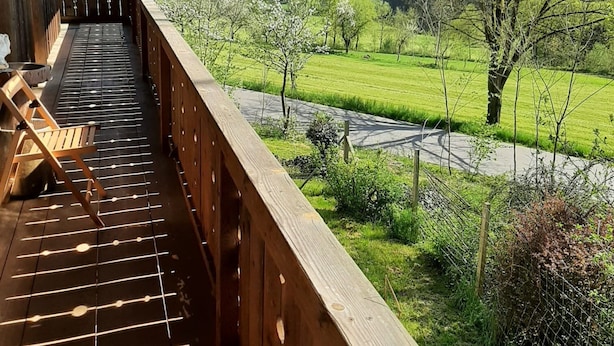 Une terrasse en bois offrant une vue sur un paysage verdoyant et une rivière.