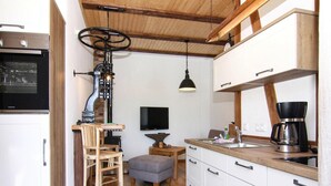 A compact kitchen with wooden flooring, white cabinets, a built-in oven, a coffee maker, and a television on the wall. - Ferienwohnung, Zemitz (Zemitz)