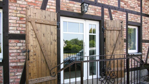 A building with a brick facade, wooden doors, and a metal railing. - Ferienwohnung, Zemitz (Zemitz)