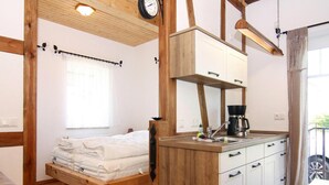A room with a bed, a wooden cabinet with drawers, a coffee maker, and a clock on the wall. - Ferienwohnung, Zemitz (Zemitz)