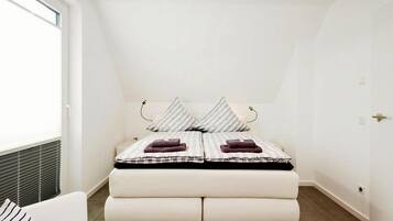 A bedroom with a bed, a chair, and a window.