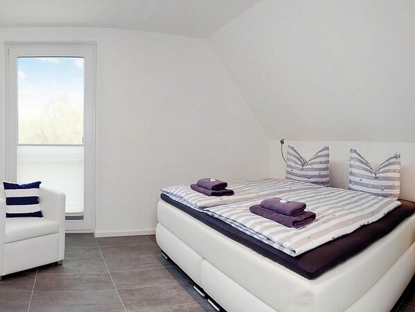 A modern bedroom with a bed, a chair, and a large window. - Aufenthalt an der Kuste auf der Insel Usedom (Peenemünde)