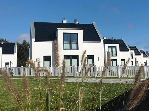 Un immeuble résidentiel moderne doté d’un toit plat, de grandes fenêtres et d’une façade blanche.