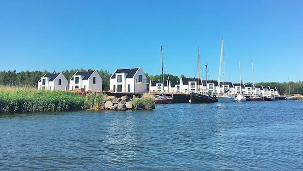 Un port de plaisance avec plusieurs maisons blanches et des voiliers amarrés.