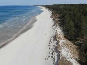 A beach with a sandy shore and a forested area. - Holiday Home in Grzybowo Near Wide Beach (Kołobrzeg)