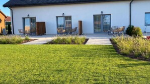 Una casa moderna de dos plantas con techo plano, grandes puertas de vidrio correderas y un césped cuidado.