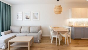 Una sala de estar moderna con un sofá, una mesa de comedor con sillas y una zona de cocina con armarios.