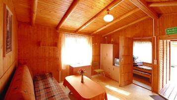Ein Holzblockhaus-Innenraum mit einer Couch, einem Tisch mit einer Vase, einem Fernseher und einer Holzkassette.