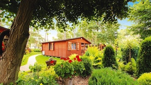 A wooden cabin surrounded by lush greenery and a garden path. - Holiday House Near the Sea, Swimming Pool, Mielno (Mielno)