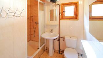 Ein Badezimmer mit Dusche, Waschbecken, Toilette und Fenster.