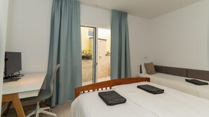 Quarto de hotel com uma escrivaninha, duas camas e vista para o exterior.