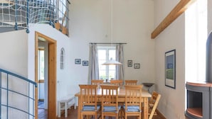 Un coin repas avec une table et des chaises en bois, une fenêtre avec des rideaux et une cheminée.