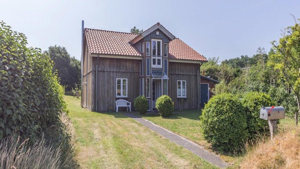 A two-story wooden house with a red-tiled roof, a front porch, and a mailbox. - Liebevoll Eingerichtetes Ferienhaus in Langenhorn (Langenhorn)