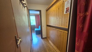 A hallway with wooden paneling, a door with a metal handle, and a red curtain.