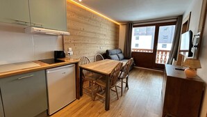 Cocina compacta con comedor, piso de madera y vistas al exterior.