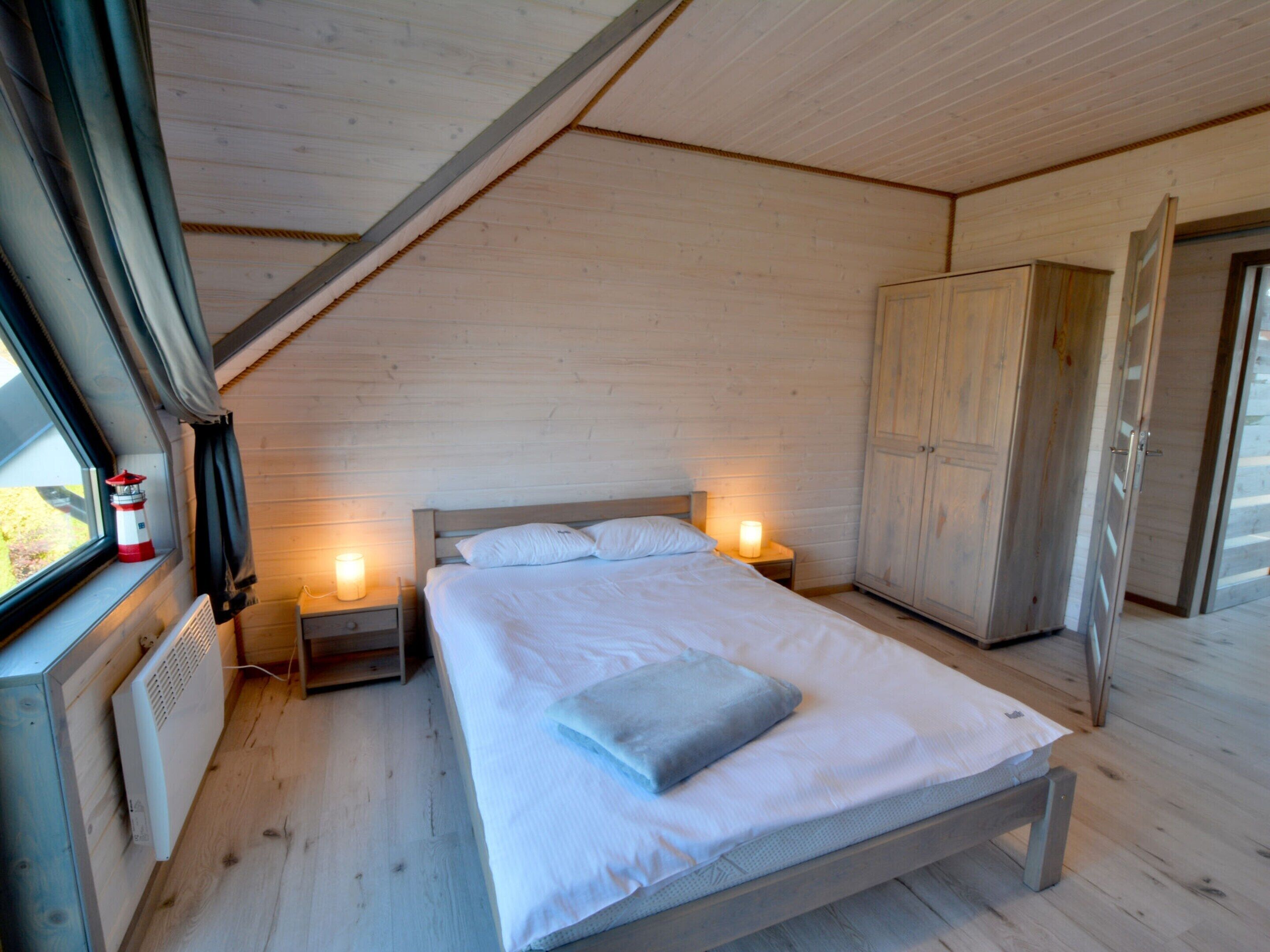 A bedroom with a wooden bed, bedside lamps, a wardrobe, and a window with curtains.