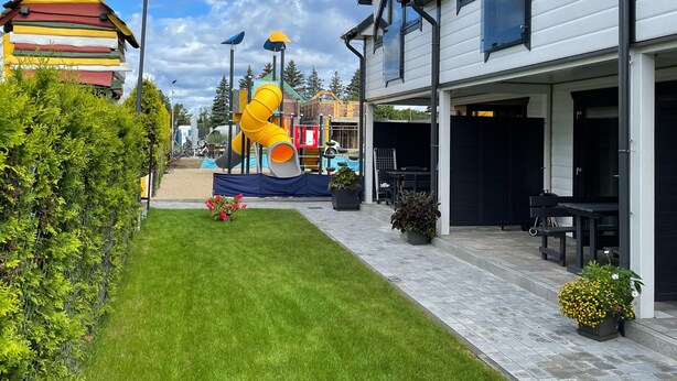 A residential area with a modern house, a colorful play structure, and a well-maintained lawn. - Comfortable Holiday Homes With air Conditioning (Ustronie Morskie)