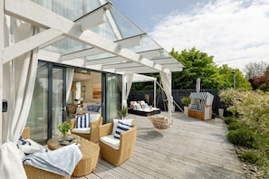 A covered outdoor area with wicker furniture, a hanging chair, and a striped chair. - House With a Huge Terrace and a Whirlpool Bathtub (Kamien Pomorski)