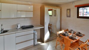 Una cocina moderna con armarios blancos, horno empotrado y comedor con sillas de madera y mesa dispuesta para cuatro.