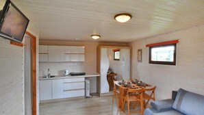 Un espacio habitable compacto con kitchenette, comedor y asientos.