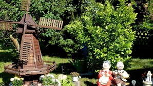 Un jardin agrémenté d’un moulin à vent, d’un étang et de statues.