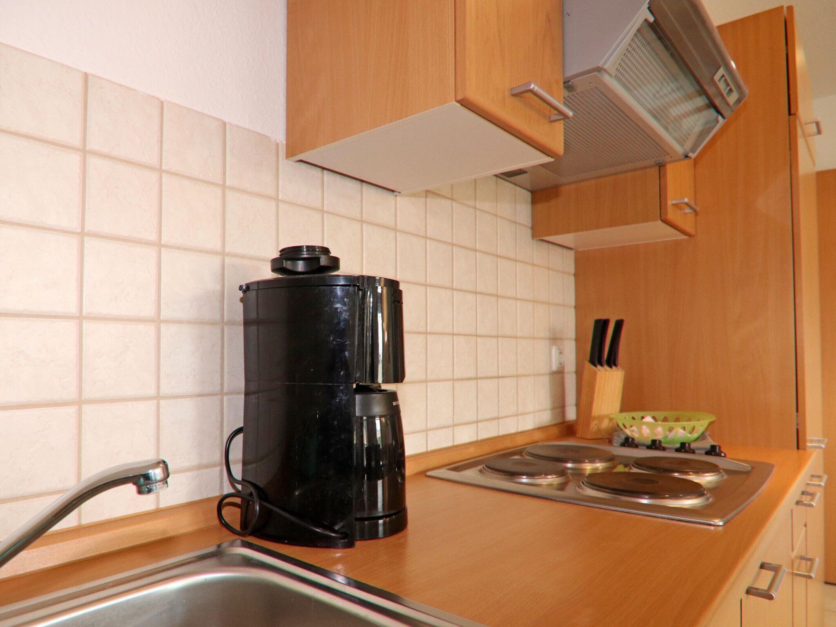 A kitchen with a coffee maker, a sink, and a stove.