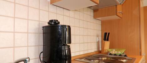 A kitchen with a coffee maker, a sink, and a stove.