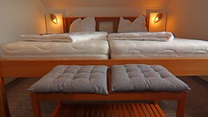 Une chambre avec un grand lit, deux tables de chevet et un banc placé au centre.