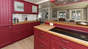 A kitchen with red cabinets, a wooden countertop, and a built-in oven. - Ferienwohnung in Wyk Boldixum for Vier Personen (Wyk auf Foehr)