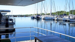 A marina with multiple sailboats docked, a wooden dock, and a covered area with railings. - Hausboot in Boltenhagen (Boltenhagen)