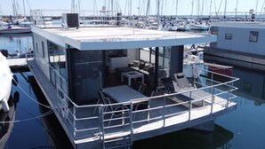 A floating structure with a dining area, outdoor seating, and a view of the marina. - Hausboot in Boltenhagen (Boltenhagen)