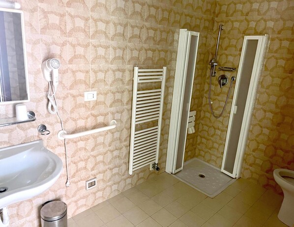 Un baño con lavamanos, inodoro, ducha y toallero.