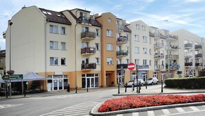 Un edifici residencial de diverses plantes amb balcons, un senyal de carrer i un massís de flors.