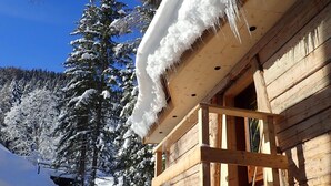 Une cabane en bois avec un toit enneigé et une véranda en bois.