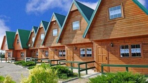 A row of wooden cabins with pitched roofs and green trim, arranged in a linear fashion. - Two-story Holiday Homes With Terraces (Mielno)