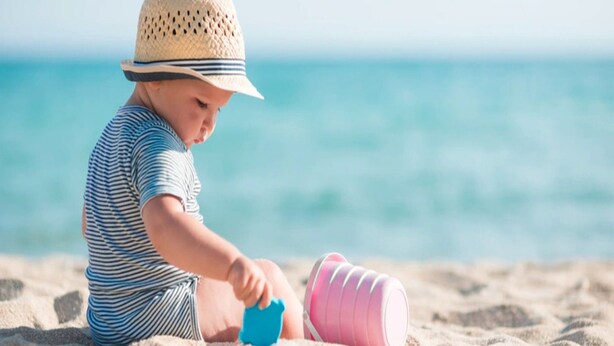 A child playing with toys on a sandy beach with the ocean in the background. - Two-story Holiday Homes With Terraces (Mielno)