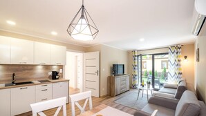 A modern apartment with a kitchen, dining area, and living room. It includes a dining table with chairs, a sofa, and a TV. - Comfortable Apartments Close to the Beach Darlowko (Darlowo)