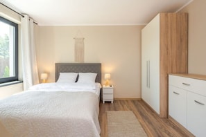 Une chambre à coucher comprenant un lit, des tables de chevet, un luminaire suspendu et des placards intégrés.